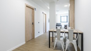 Un pasillo con puertas de madera, un comedor con mesa y sillas, y vista a una habitación con ventana.
