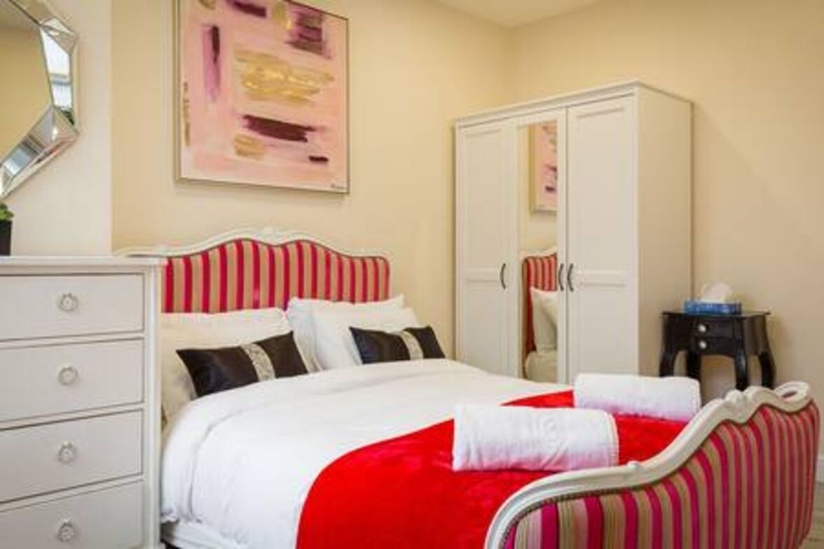Un dormitorio con cama, cómoda, armario y espejo.