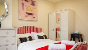 Un dormitorio con cama, cómoda, armario y espejo.