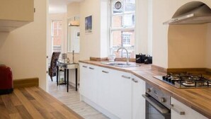 Una cocina moderna con armarios blancos, una encimera de madera y una estufa a gas.