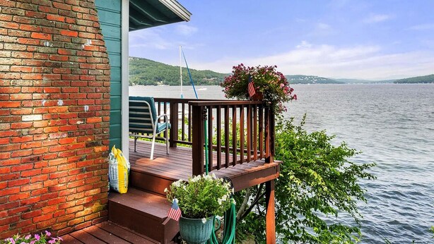 Eine Holzterrasse mit Geländer, einem Stuhl und einem Blumentopf mit einer amerikanischen Flagge.