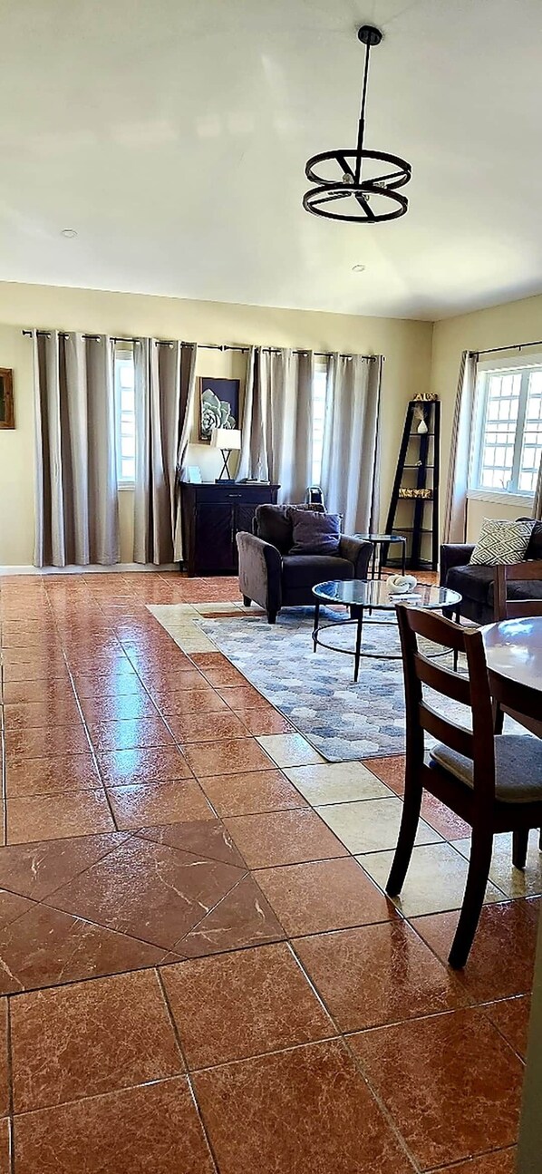 A spacious living area with a dining table, chairs, a sofa, and a coffee table.