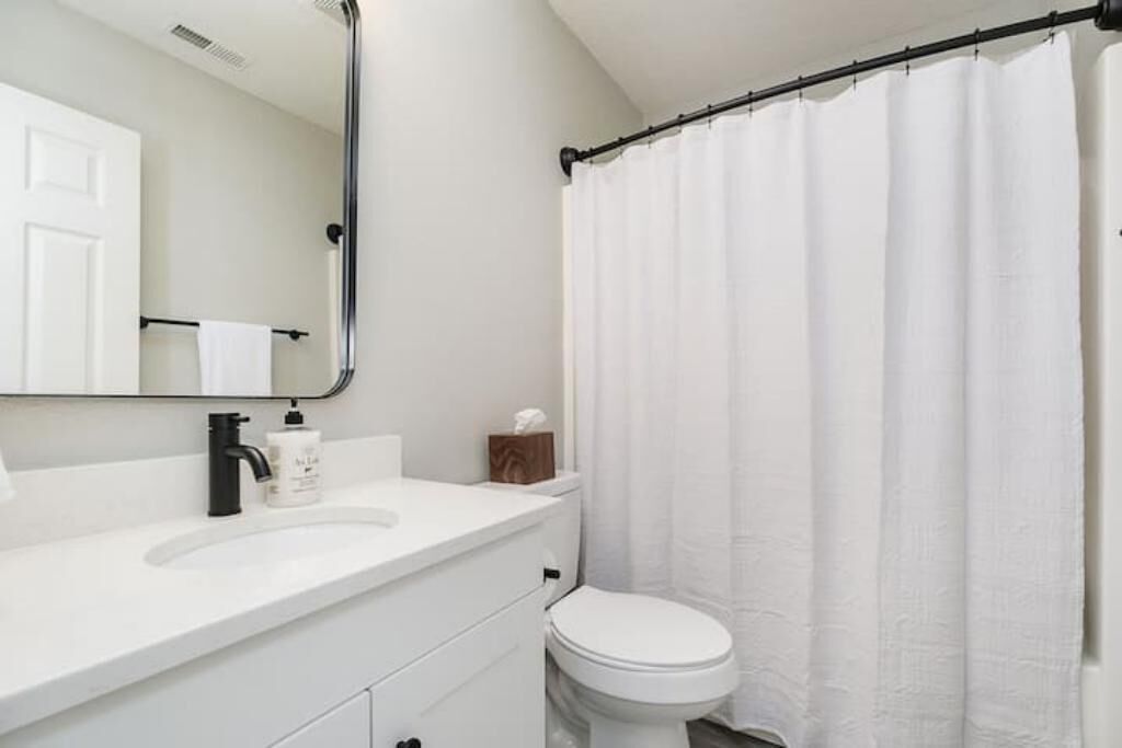 A bathroom with a white sink, a toilet, and a shower curtain.