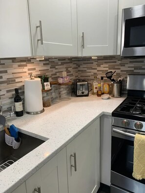 A modern kitchen with white cabinets, a stainless steel stove, and a tiled backsplash.