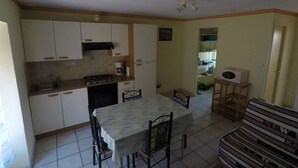 A compact kitchen with a dining table and chairs, a microwave, and a small refrigerator.