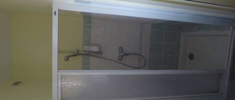 A bathroom with a shower enclosure, a hand soap dispenser, and a towel rack.