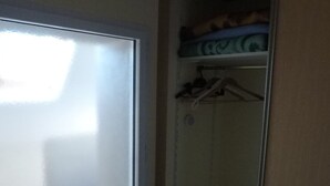 A room with a sliding door leading to a closet with shelves and hanging space.