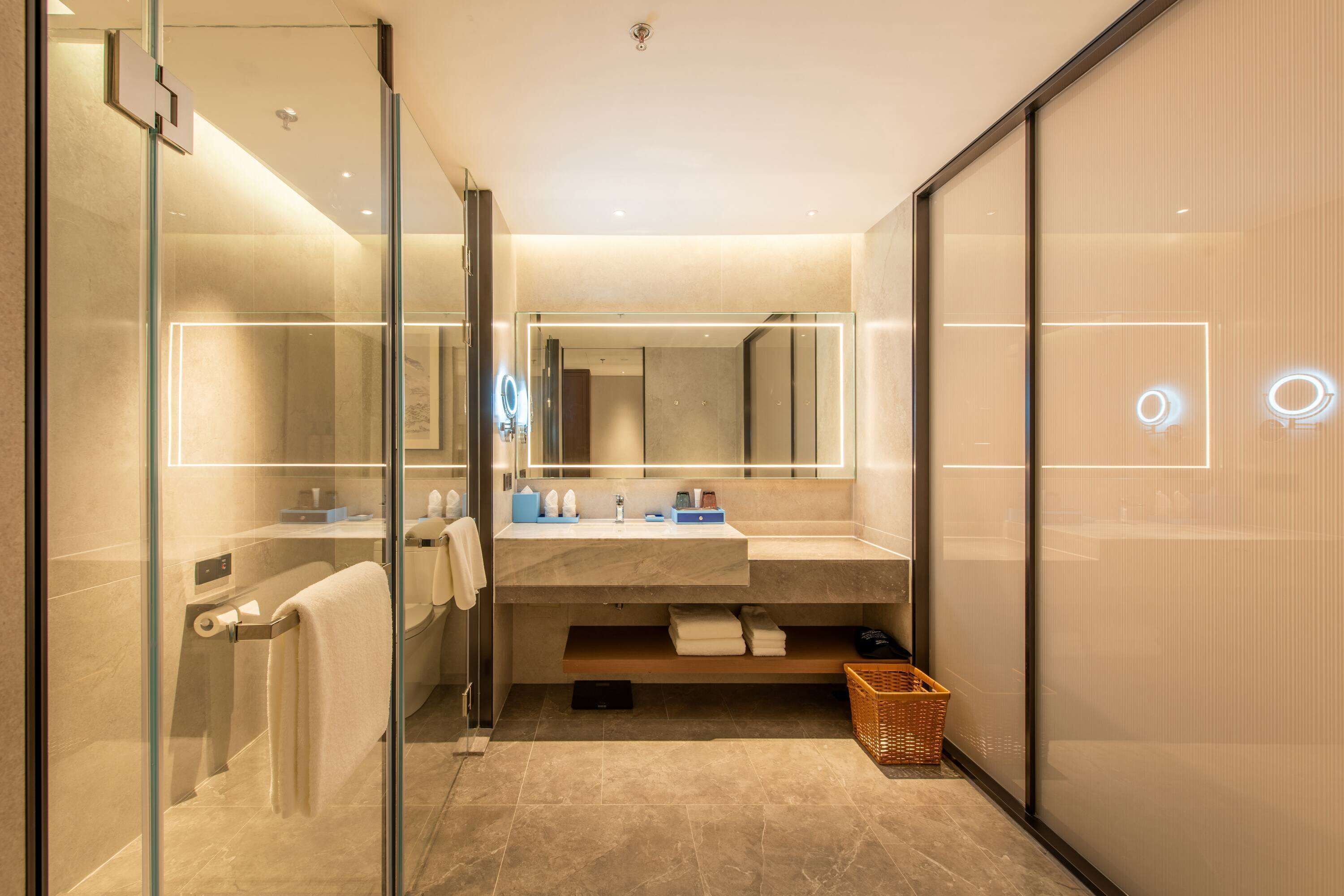 A modern bathroom with a glass shower enclosure, a large mirror, and a vanity with a sink and towel rack.