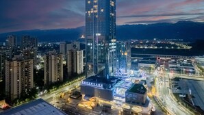 A high-rise building with multiple floors, surrounded by other buildings and a busy road with moving vehicles. - HOJO China Communications Construction Plaza Chongqing (Chongqing)