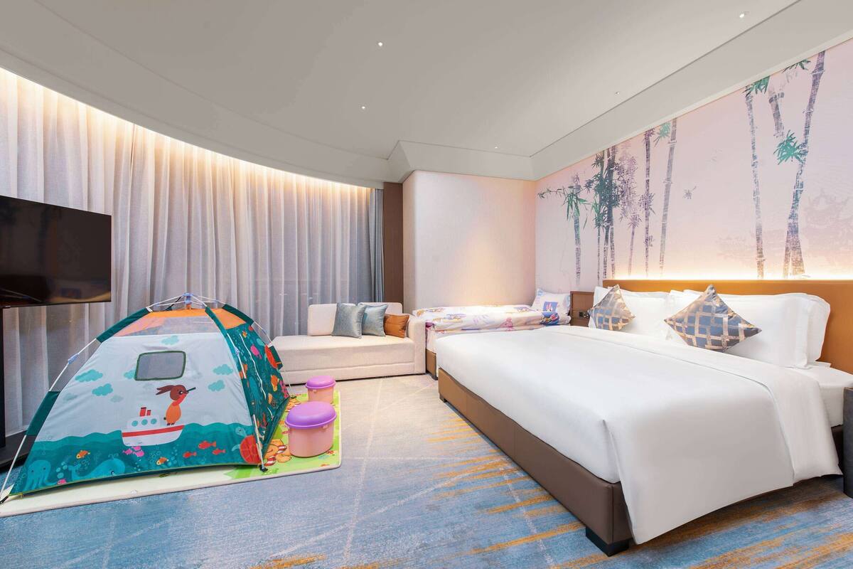 Ein Hotelzimmer mit einem Bett, einem Zelt, einem Sofa und einem Fernseher.