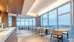 A modern dining area with large windows, wooden flooring, and contemporary furniture. - HOJO China Communications Construction Plaza Chongqing (Chongqing)