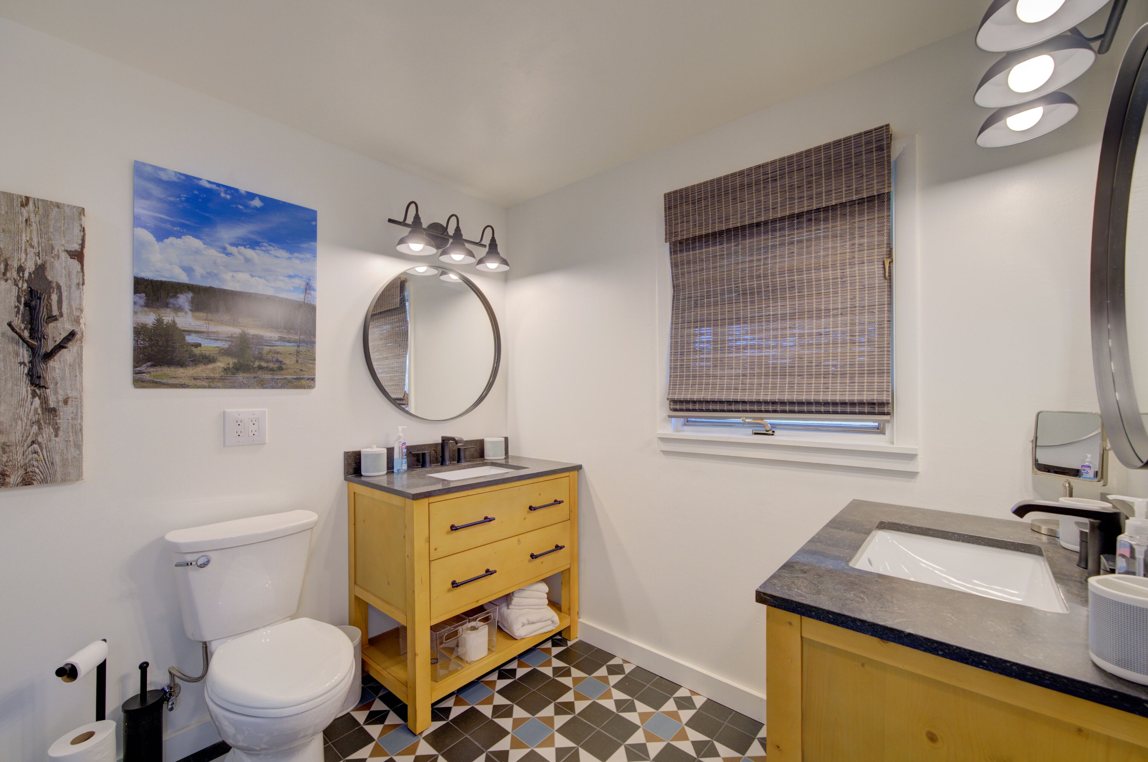 A bathroom with a toilet, wooden vanity, sink, and a mirror.