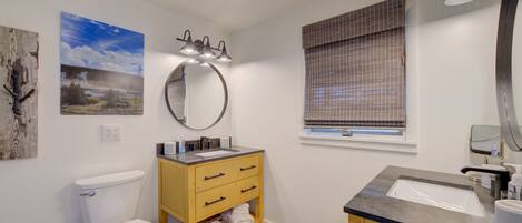 A bathroom with a toilet, wooden vanity, sink, and a mirror.