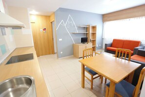 Een knus woongedeelte met kitchenette, eethoek, een bank en een televisie op een houten kast.