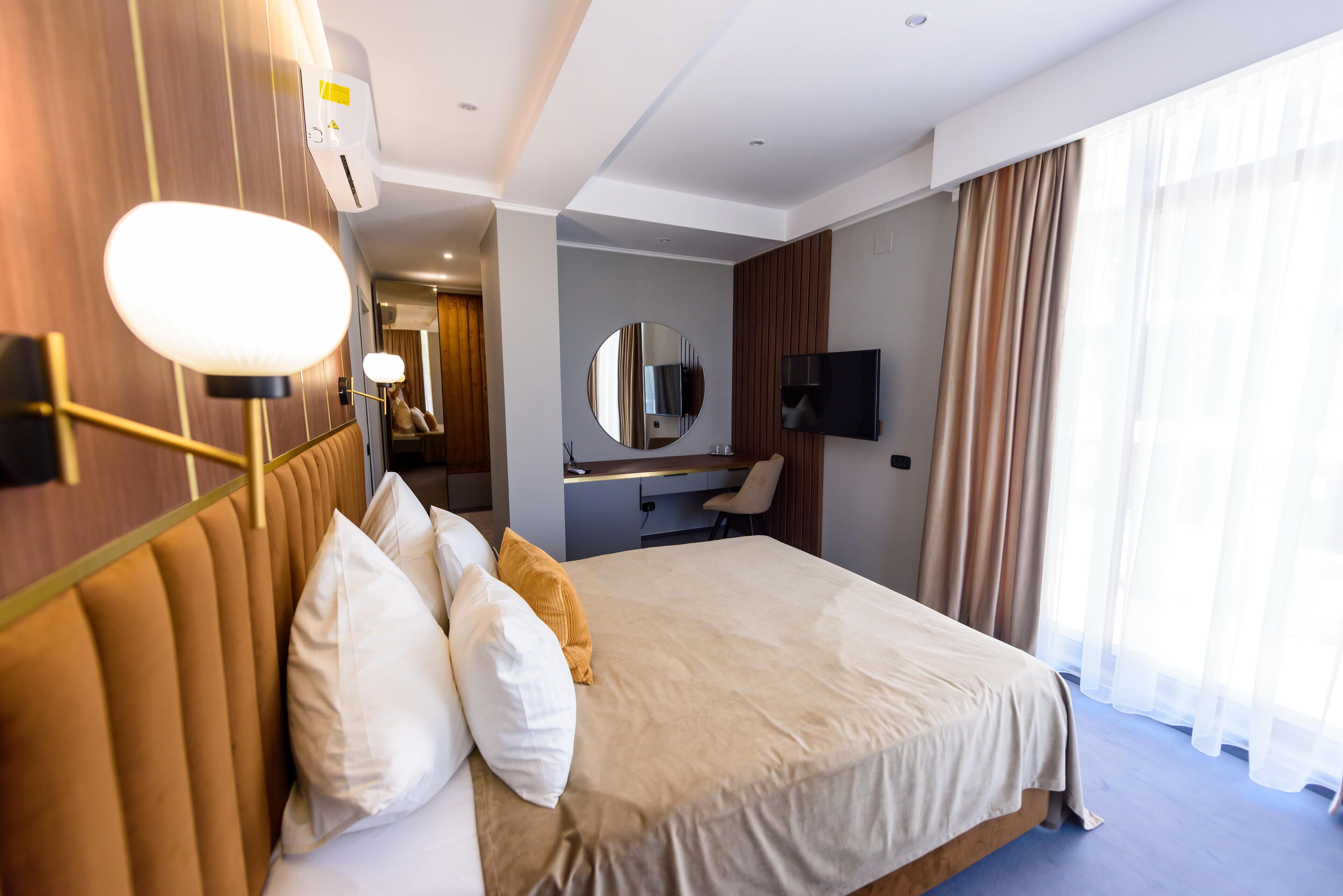 Una habitación de hotel con una cama grande, un escritorio con una silla, un televisor y un espejo.