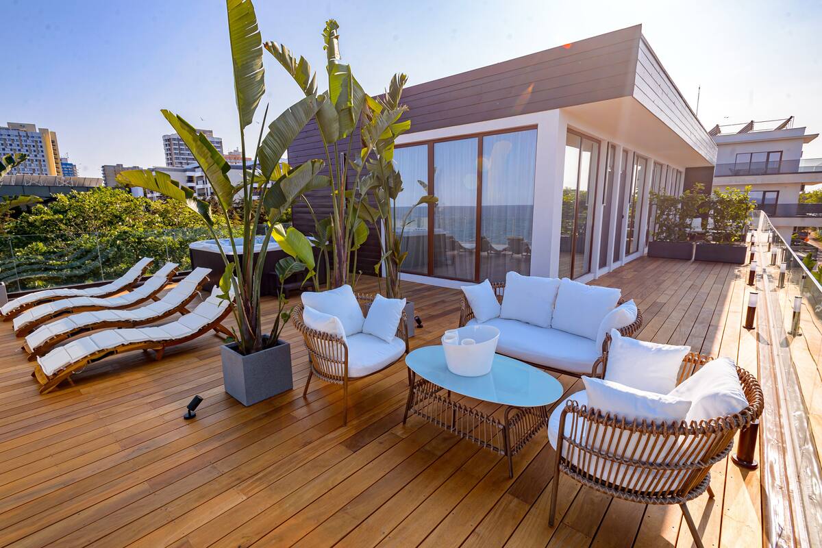 A rooftop deck with lounge chairs, a sofa, and a coffee table.