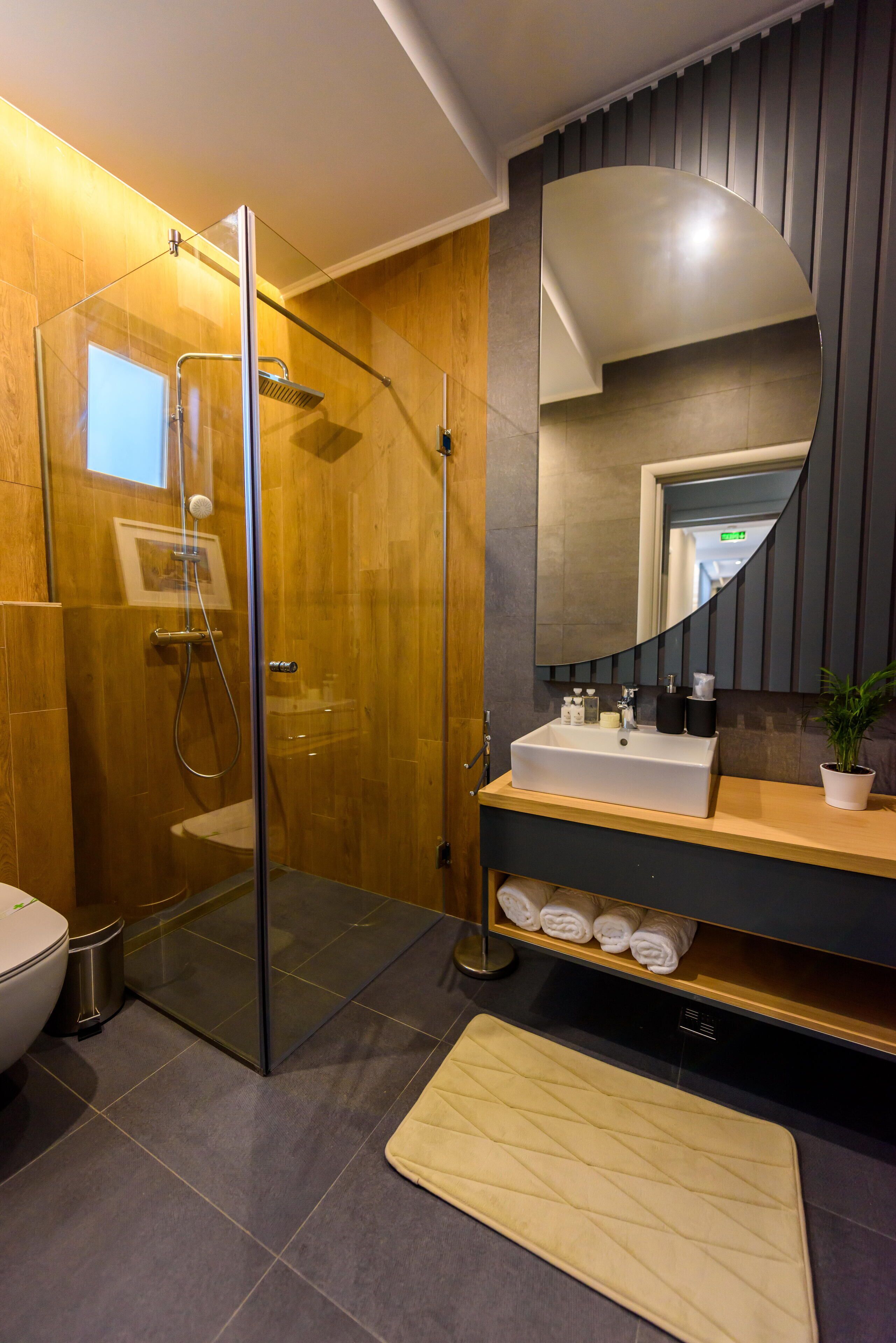 A modern bathroom with a glass-enclosed shower, a vanity with a sink, and a large mirror.