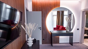 A modern interior with a wooden wall, a round mirror, a dark table, and a red sofa.