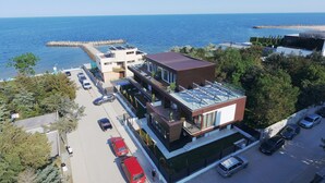A modern building with a rooftop terrace, a parking area, and a view of the sea.