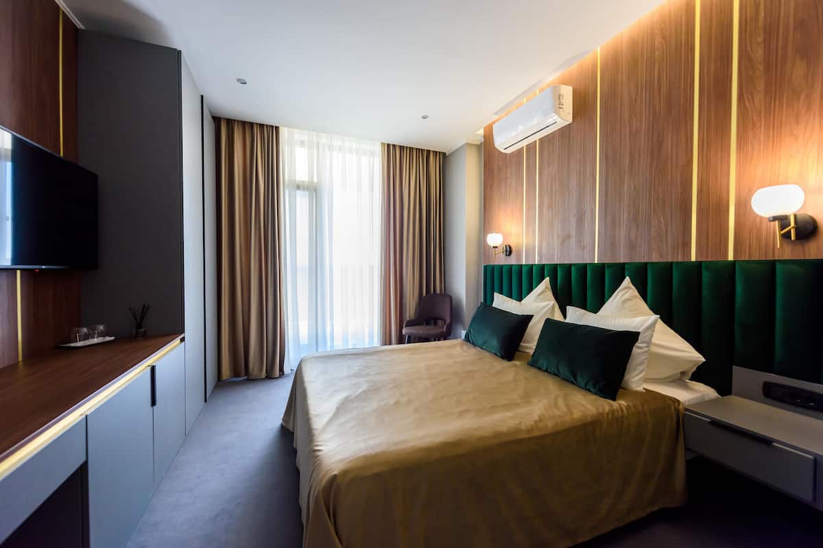 A hotel room with a bed, a desk, a chair, and a television.