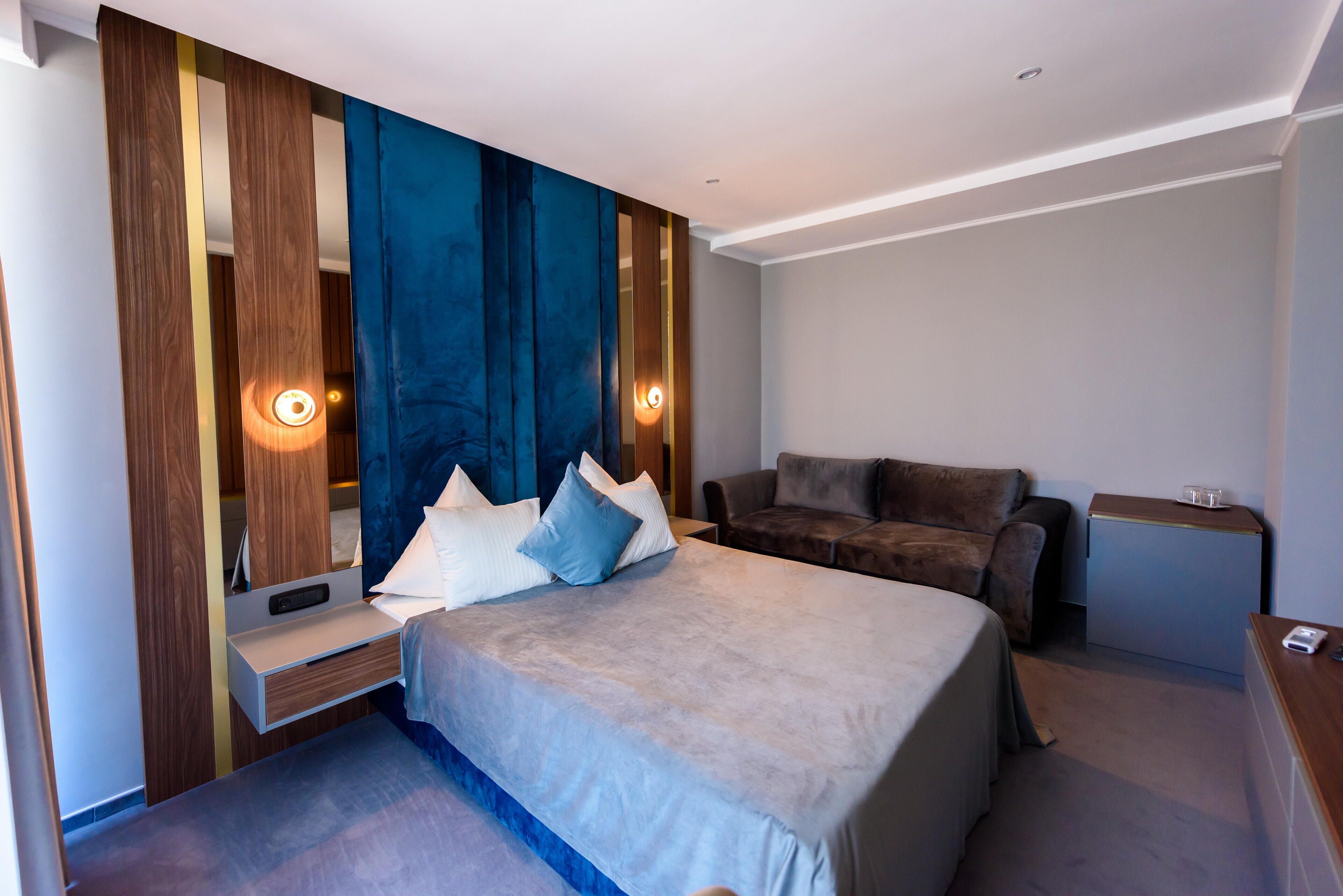 Ein modernes Hotelzimmer mit einem großen Bett, einer Couch, einem Schreibtisch und einem Kleiderschrank.