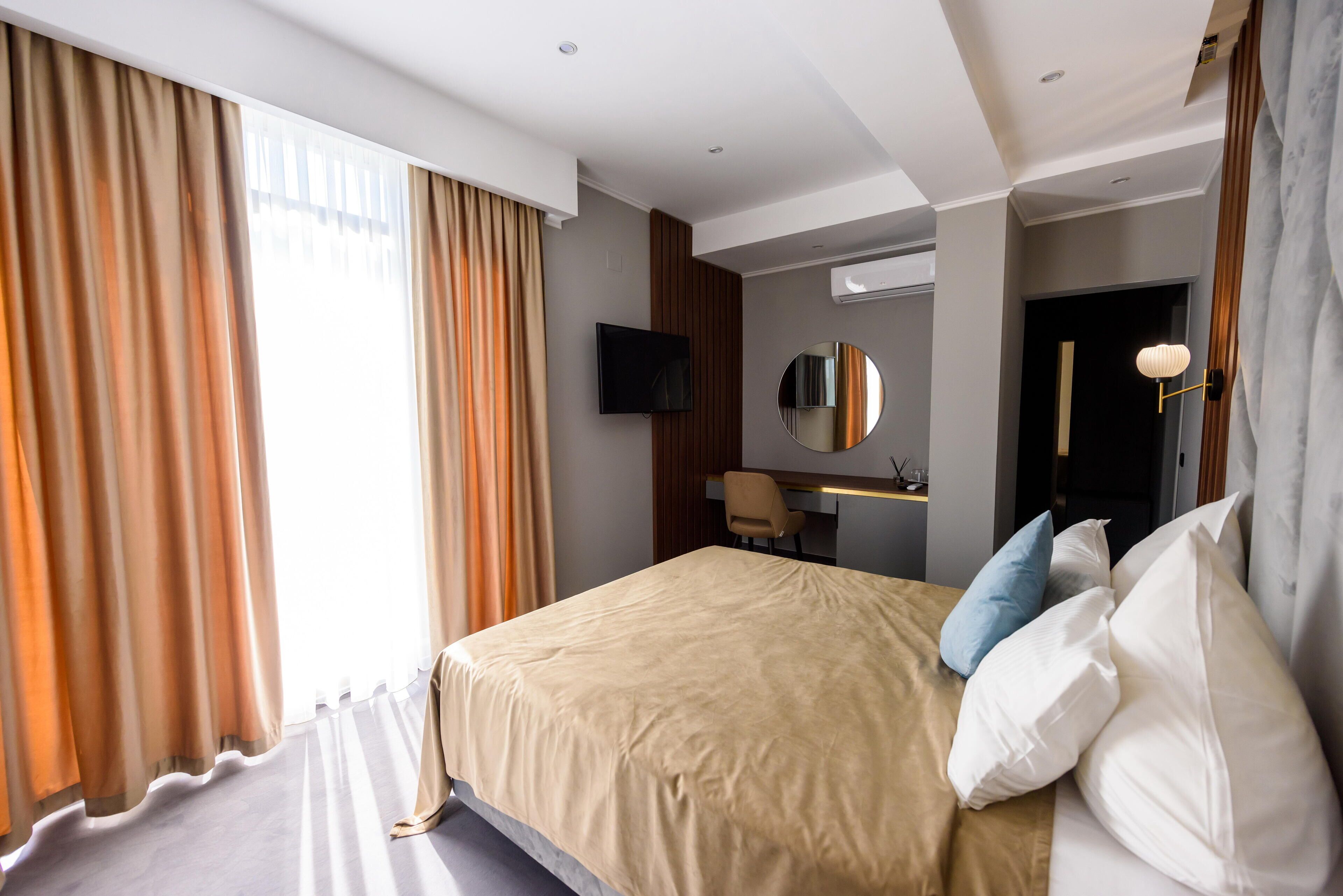 Une chambre d’hôtel avec un grand lit, un bureau, une chaise, une télévision et un miroir.