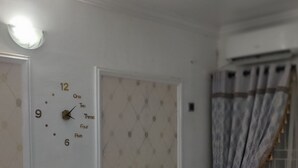 Une pièce avec un canapé blanc, une horloge murale et une fenêtre avec des rideaux.