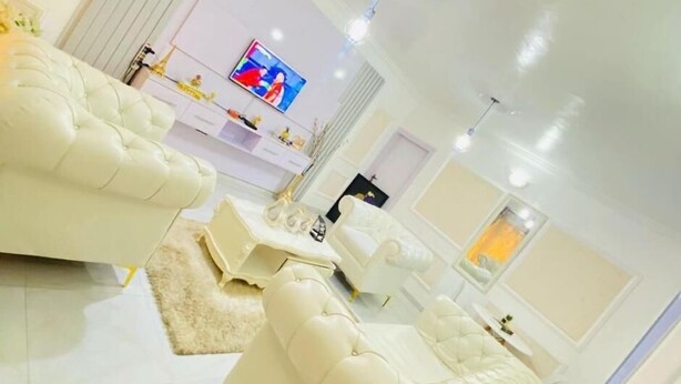 Un salon moderne avec un canapé blanc, un téléviseur à écran plat et une décoration minimaliste.