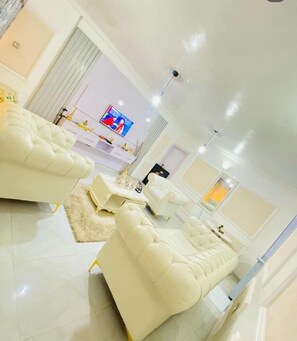 Un salon moderne avec un canapé blanc, un téléviseur à écran plat et une décoration minimaliste.