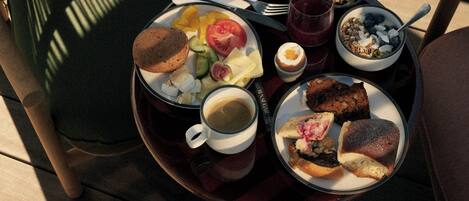 Bandeja con alimentos para el desayuno, incluyendo pan, fruta y una taza de café.