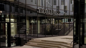 The exterior of The Cloud Hotel with a glass facade, a staircase leading to the entrance, and a well-lit entrance area. - The Cloud One Prague (Prague)