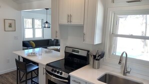 A modern kitchen with white cabinets, a black stove, and a stainless steel sink. - Nordic Hideaway on Silverthorn Lake - Little Sisu (Hayward)