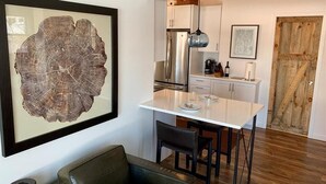 A compact kitchen with a white countertop, stainless steel appliances, and a hanging pendant light. - Nordic Hideaway on Silverthorn Lake - Little Sisu (Hayward)