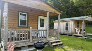 Un chalet rustique doté d’une véranda, d’un barbecue et d’une petite table.