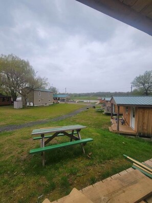 Un terrain de camping doté de cabanes en bois, de tables de pique-nique et d’une zone herbeuse.