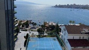A high-rise building with a tennis court and a view of the sea.