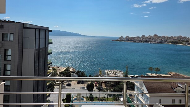 A coastal cityscape with a view of the sea and distant mountains.