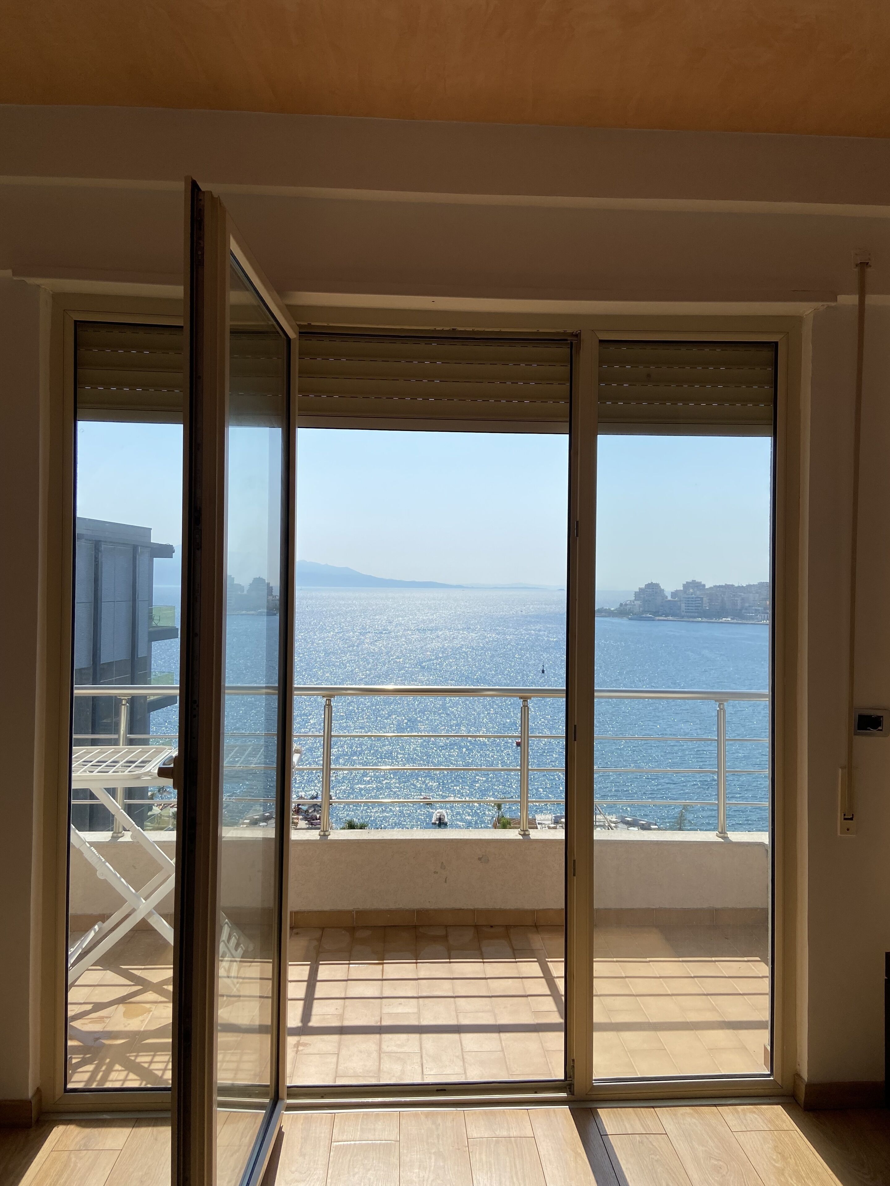 A balcony with a view of the sea and distant buildings.