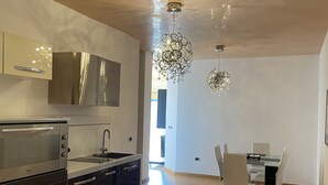 A modern kitchen with a built-in oven, stainless steel cabinets, and a dining area with a table and chairs.