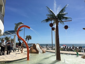 Un espace piscine agrémenté d’un élément décoratif aquatique, de palmiers et offrant une vue sur l’océan.