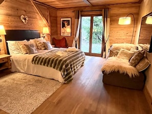 Een knus slaapkamer in een houten chalet, met een bed, een bank en een groot raam.