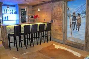 Een bar met houten wanden, een kleden van leer en een schilderij van skiërs.
