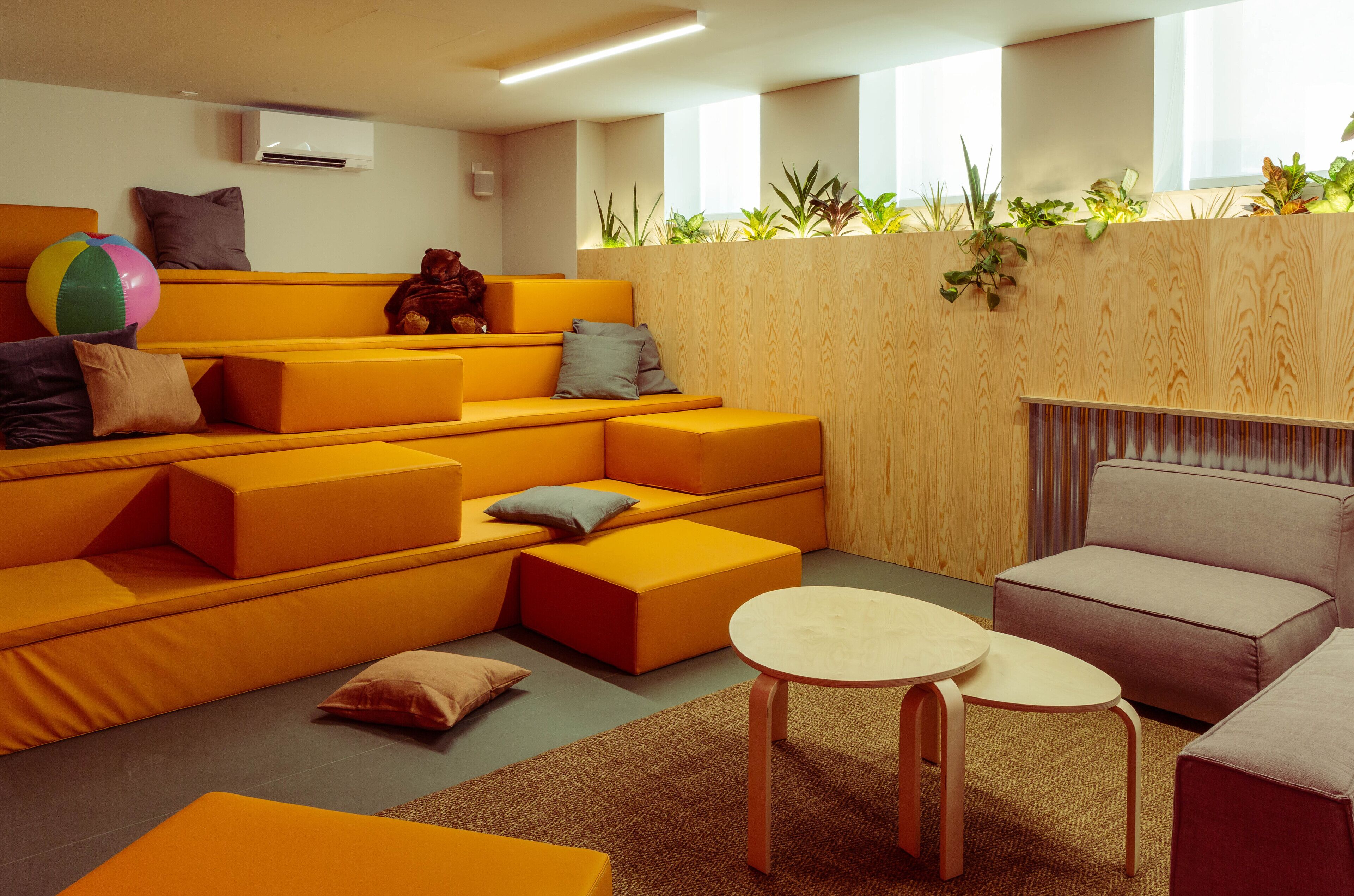 A modern living room with orange sofas, a round table, and a grey armchair.