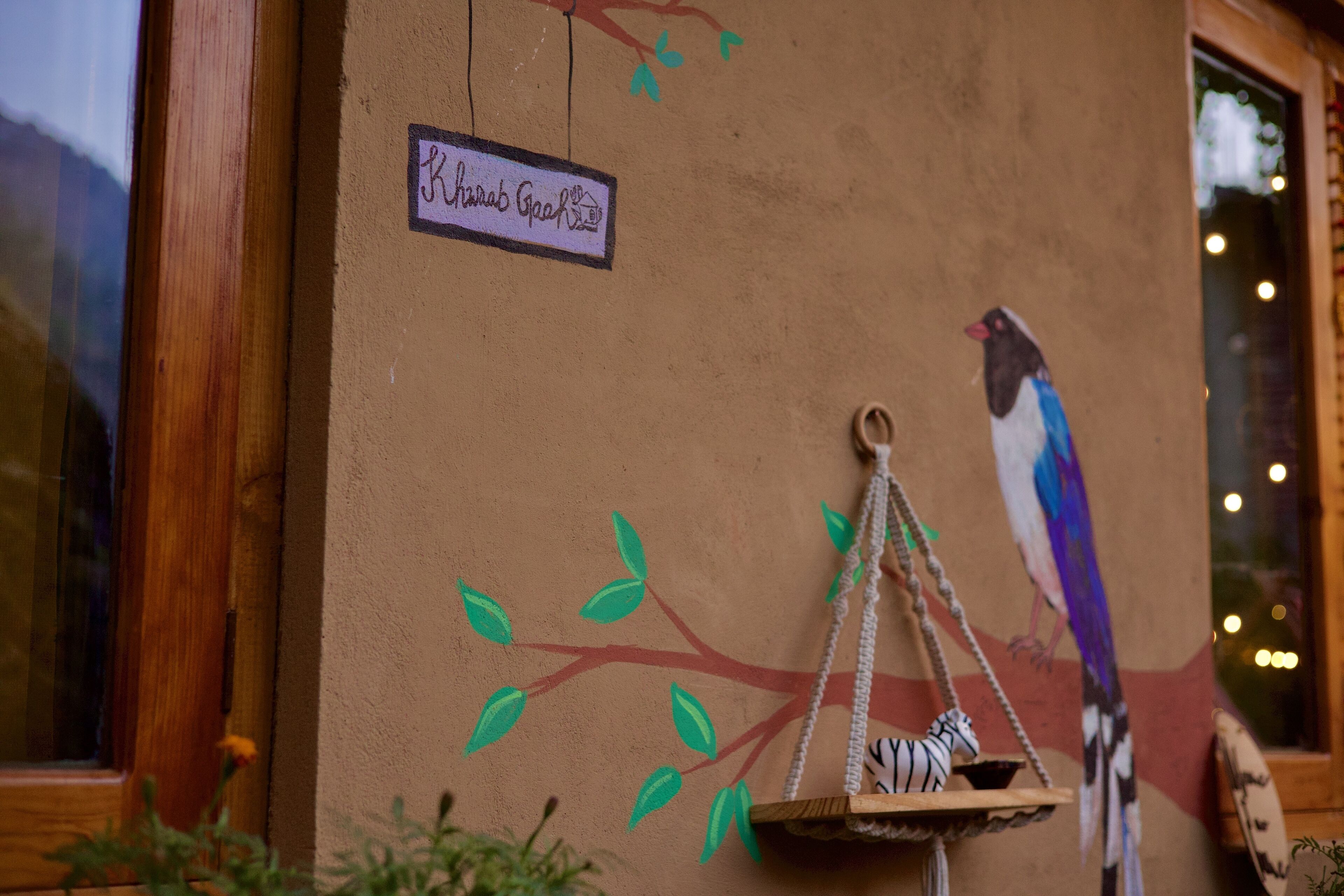 A wall with a bird mural, a hanging birdcage, and a sign reading "Rhinobee Rooftop".