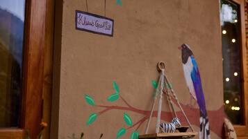 A wall with a bird mural, a hanging birdcage, and a sign reading "Rhinobee Rooftop".
