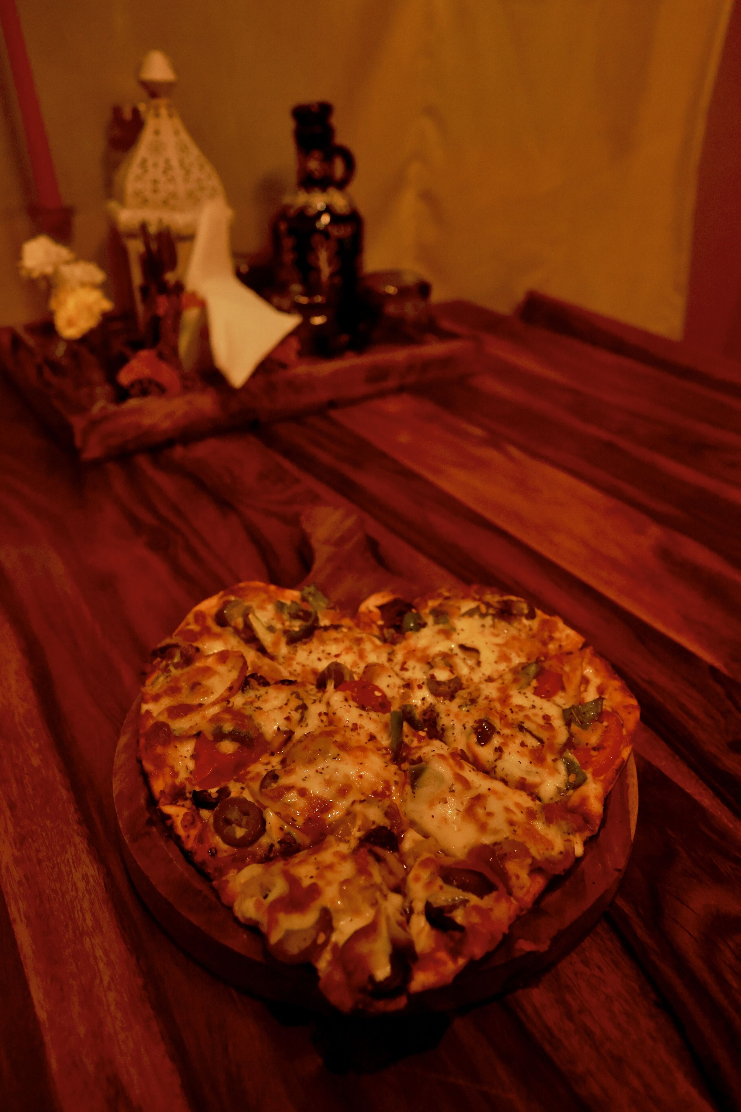 A pizza on a wooden tray on a table.