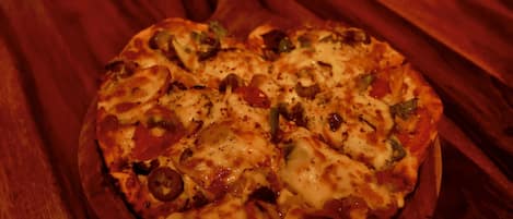 A pizza on a wooden tray on a table.