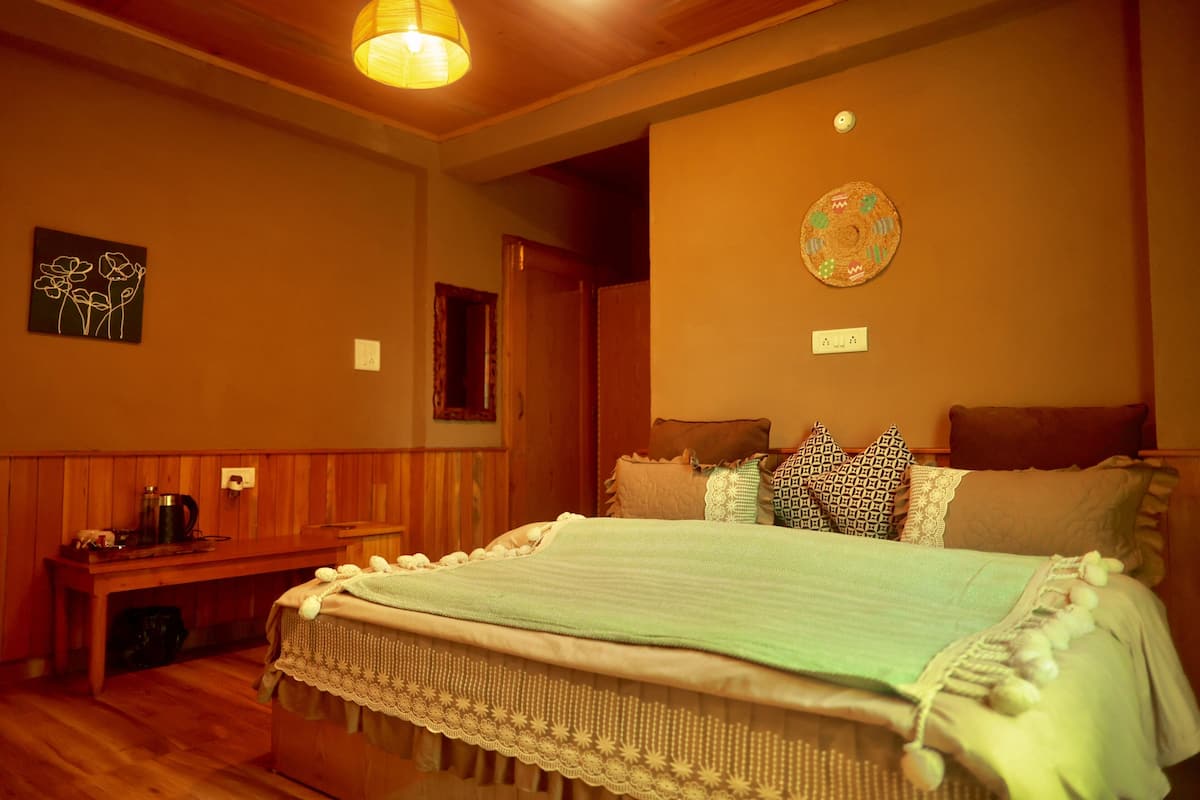 A cozy bedroom with a wooden bed, a bedside table, a lamp, and a wall art piece.