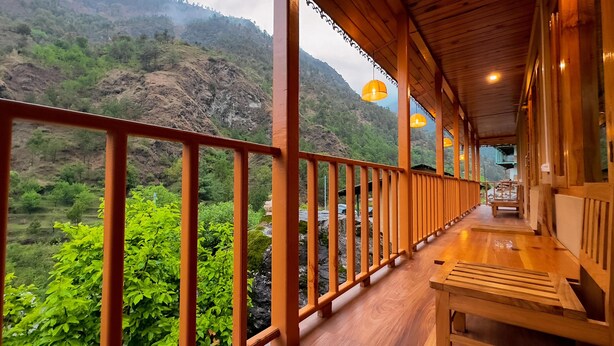 A wooden balcony with a view of a mountainous landscape. - Khwaabgaah-A Boutique Homestay (Banjar)