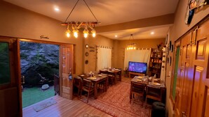 A cozy dining area with wooden furniture, a television, and a view of the outdoors. - Khwaabgaah-A Boutique Homestay (Banjar)